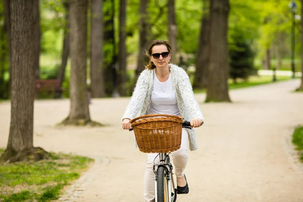 春の公園で女性の自転車に乗ってカジュアルな服装で大人の女性 — ストック写真