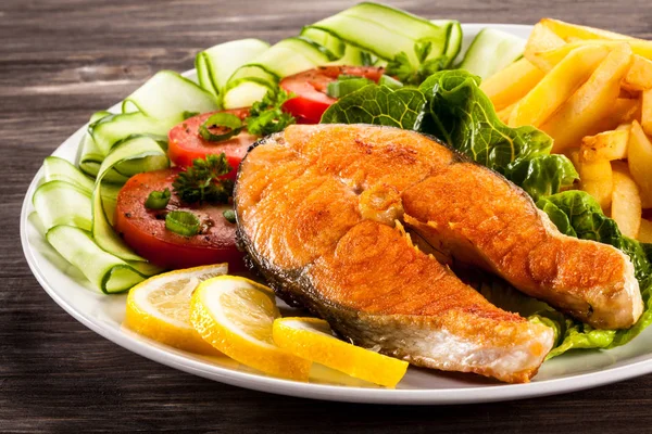 烤鲑鱼配法式薯条 切片蔬菜和柠檬白盘子 — 图库照片