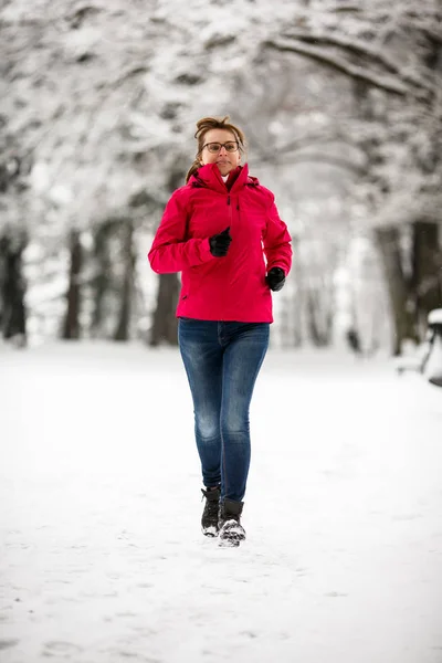 冬に都市公園で走っている中年女性 — ストック写真