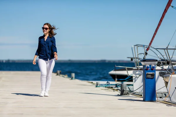 カジュアルな服装と海辺でウォーキング サングラスの若い女性 — ストック写真