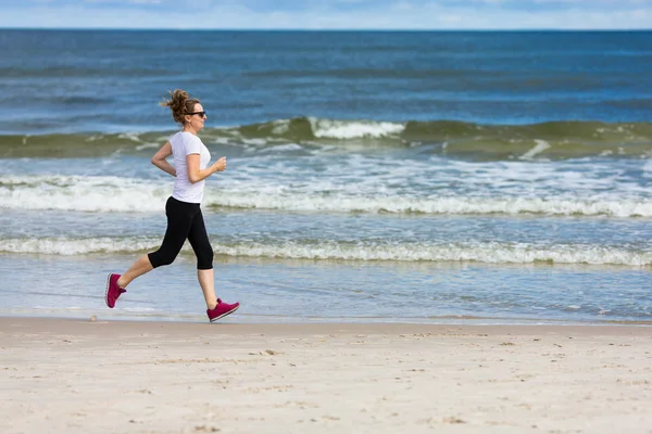 活跃运动的成年妇女跑在海边 — 图库照片
