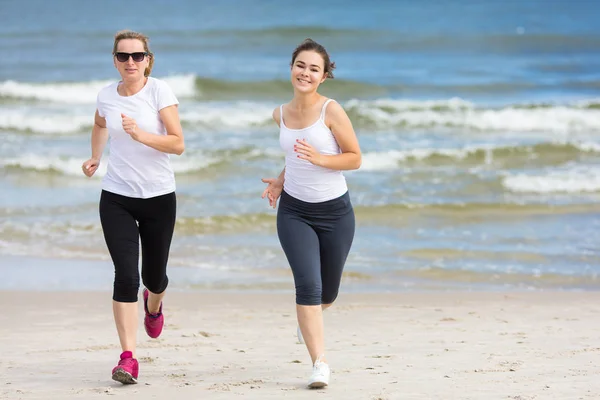 アクティブな十代の女の子と海で一緒にジョギングの女性 — ストック写真