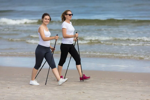 活跃的十几岁的女孩和妇女一起散步与旅游棍子在海边 北欧步行 — 图库照片