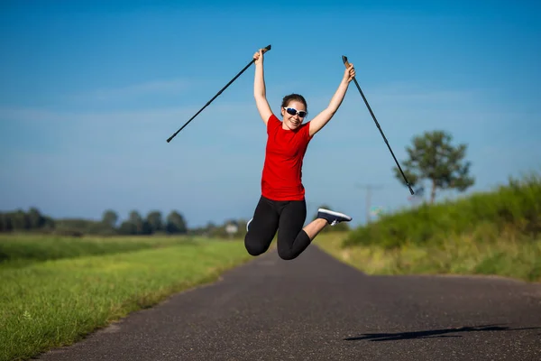 Jonge Vrouw Sportkleding Springen Met Plezier Met Toeristische Stokken — Stockfoto