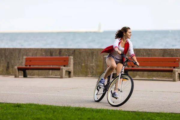 活跃的年轻妇女骑自行车在海边 — 图库照片