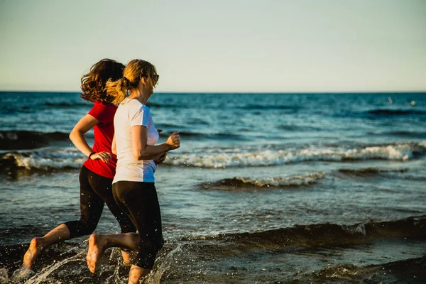 アクティブな十代の女の子と海で一緒にジョギングの女性 — ストック写真