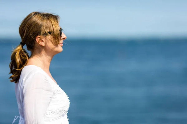 穿着白色礼服和太阳镜的妇女的画像摆姿势在海边 — 图库照片