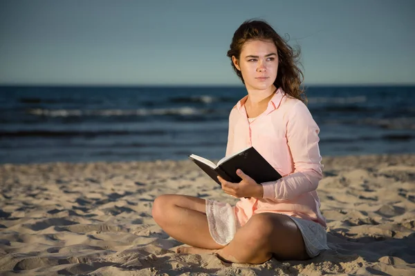 年轻女孩在礼服读书在海边 — 图库照片