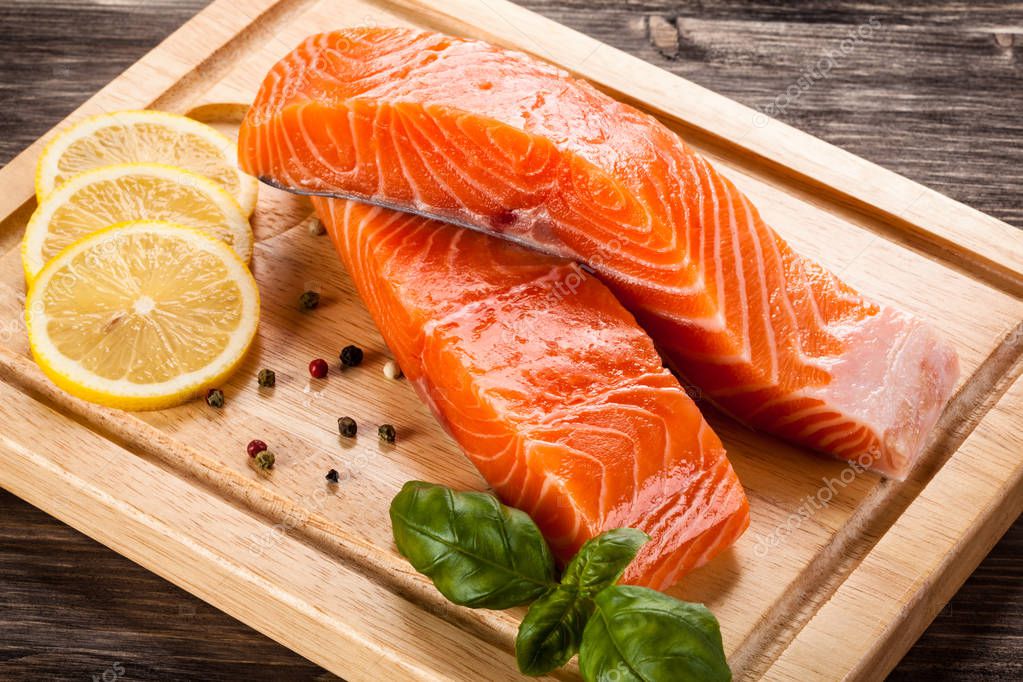 Trozos de salmón crudo con limón, granos de pimienta y albahaca sobre