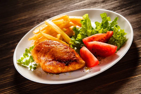 烤鸡胸肉配薯条 新鲜西红柿 生菜在木桌背景上的白色盘子上 — 图库照片