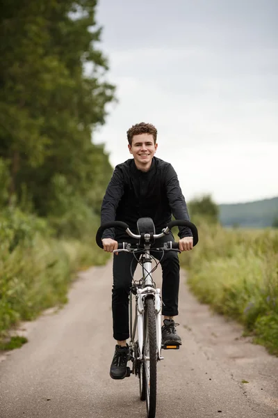 穿着深色休闲服的年轻人骑自行车在户外 — 图库照片