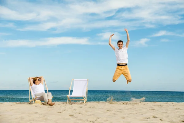 Son Mother Having Fun Seaside Man Jumping Woman Relaxing Sunbed — Stock Photo, Image