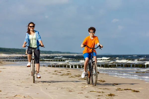 健康的年轻女孩和男孩骑自行车在海边 — 图库照片