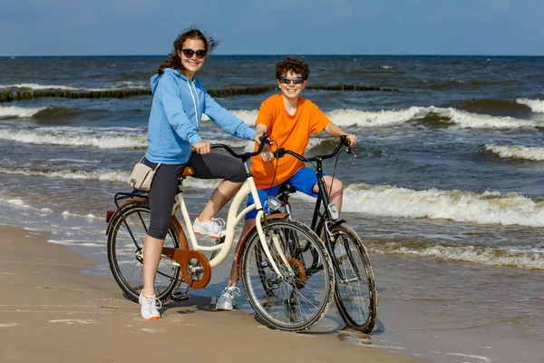 健康的年轻女孩和男孩骑自行车在海边 — 图库照片