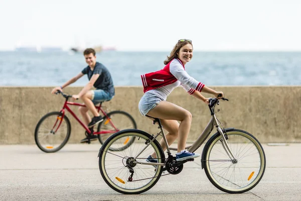 健全な若い女の子と男の子の海辺で自転車に乗って — ストック写真