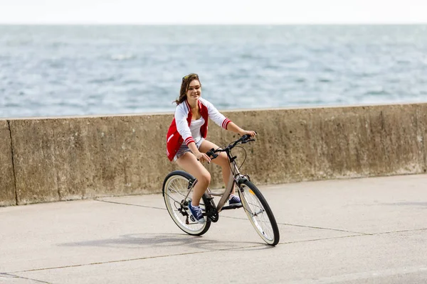 在海边骑自行车的少女 运动和休闲概念 — 图库照片