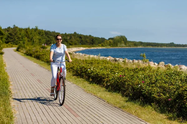 海辺でアクティブなスポーティな女性乗馬自転車 — ストック写真