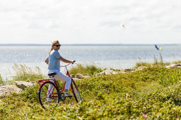夏の海辺でポーズをとってバイクを持つ女性 — ストック写真