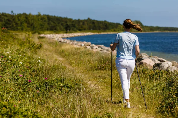 Γυναίκα Λευκά Ρούχα Casual Περπάτημα Στο Seaside Χρησιμοποιώντας Ραβδιά Τουριστικά — Φωτογραφία Αρχείου