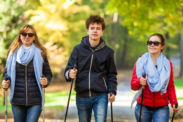 Alegre Familia Caminando Juntos Parque Otoñal Con Palos Turísticos — Foto de Stock