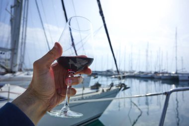 Erkek el ile yat arka plan üzerinde kırmızı şarap tutarak 