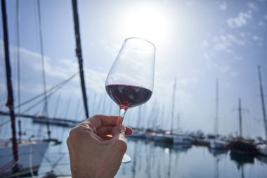 Erkek el ile yat arka plan üzerinde kırmızı şarap tutarak 