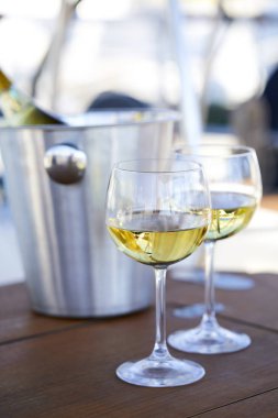 Çift kadehlerin ve kova yatında şampanya şişesi ile