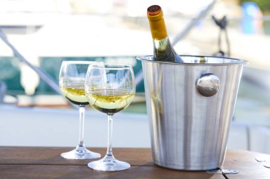 Çift kadehlerin ve kova yatında şampanya şişesi ile