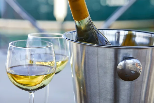 Çift kadehlerin ve kova yatında şampanya şişesi ile