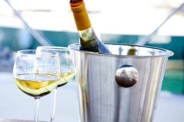 Çift kadehlerin ve kova ile yatta beyaz şarap şişesi