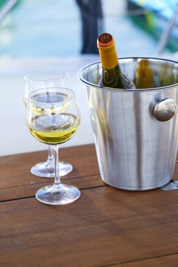 Çift kadehlerin ve kova ile yatta beyaz şarap şişesi
