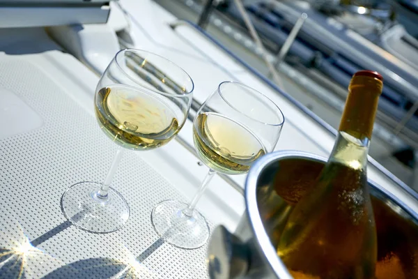 Pair of wineglasses and bucket with white wine bottle on yacht