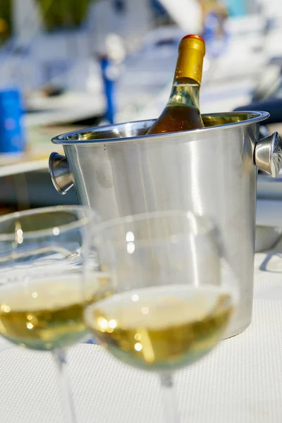 Pair of wineglasses and bucket with white wine bottle on yacht