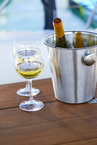 Çift kadehlerin ve kova ile yatta beyaz şarap şişesi