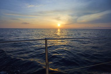 turuncu günbatımında denizde yüzen yat 