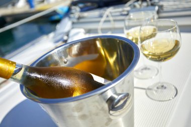 Çift kadehlerin ve kova ile yatta beyaz şarap şişesi