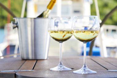 Çift kadehlerin ve kova ile yatta beyaz şarap şişesi