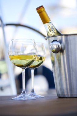 Çift kadehlerin ve kova ile yatta beyaz şarap şişesi