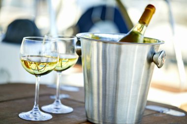 Çift kadehlerin ve kova ile yatta beyaz şarap şişesi