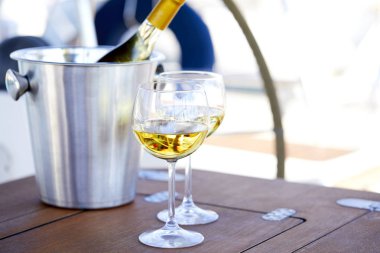 Çift kadehlerin ve kova ile yatta beyaz şarap şişesi