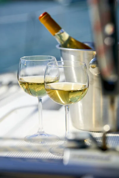 Pair of wineglasses and bucket with white wine bottle on yacht