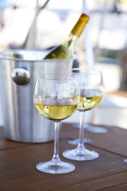 Çift kadehlerin ve kova ile yatta beyaz şarap şişesi
