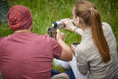 güneşli gün çayır üzerinde oturan termos ile iki seyahat etmek 
