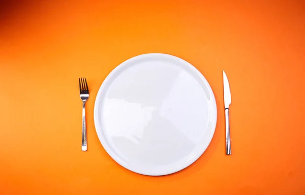 Άδειο Πιάτο Πιρούνι Και Μαχαίρι Πορτοκαλί Φόντο Γκρο Πλαν — Φωτογραφία Αρχείου