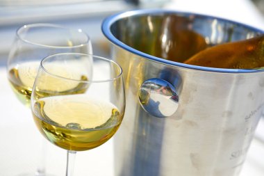 Çift kadehlerin ve kova ile yatta beyaz şarap şişesi