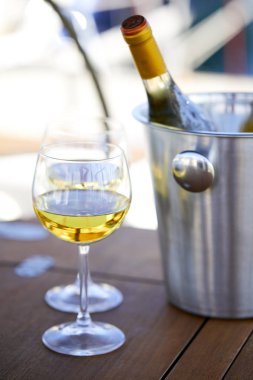 Çift kadehlerin ve kova ile yatta beyaz şarap şişesi
