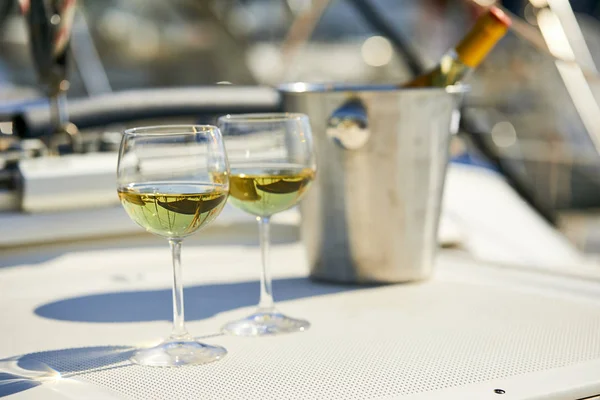 Pair of wineglasses and bucket with white wine bottle on yacht