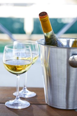Çift kadehlerin ve kova ile yatta beyaz şarap şişesi