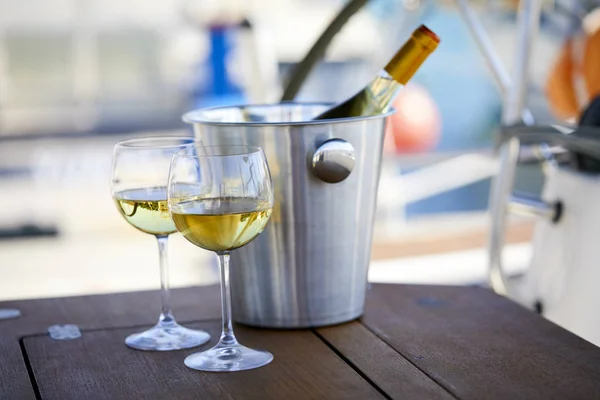 Pair of wineglasses and bucket with white wine bottle on yacht