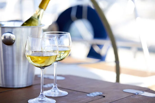 Pair of wineglasses and bucket with white wine bottle on yacht